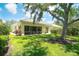 Home's back exterior featuring a screened-in lanai, patio, and lush landscaping that provides privacy at 5877 Ferrara Dr, Sarasota, FL 34238