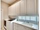 Bright laundry room with white cabinets, a sink, and modern washer and dryer at 5877 Ferrara Dr, Sarasota, FL 34238