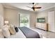 Well-lit bedroom with wood floors, ceiling fan, back yard view, and a dresser with a TV at 5877 Ferrara Dr, Sarasota, FL 34238