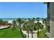 Expansive beach and ocean views featuring palm trees and a well maintained green lawn at 5916 Midnight Pass Rd # 404, Sarasota, FL 34242