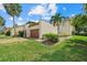 Beige exterior with a two-car garage and lush landscaping featuring a palm tree and vibrant green lawn at 6207 Courtside Dr # 23, Bradenton, FL 34210