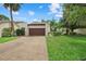 Beige single-Gathering home featuring a brown two-car garage, driveway, and front lawn at 6207 Courtside Dr # 23, Bradenton, FL 34210