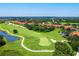 Aerial view of a golf course with a green, sand trap and pond, with tan buildings surrounded by trees at 7179 Boca Grove Pl # 202, Lakewood Ranch, FL 34202