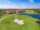 Aerial view of condos with terracotta roofs overlooking a lush green golf course with water features at 7179 Boca Grove Pl # 202, Lakewood Ranch, FL 34202