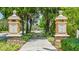 Community entrance with decorative stone pillars, lush landscaping, and a tree-lined walkway at 7179 Boca Grove Pl # 202, Lakewood Ranch, FL 34202