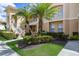 Close-up of a home's exterior with lush landscaping, staircase, balcony, and palm trees at 7179 Boca Grove Pl # 202, Lakewood Ranch, FL 34202