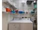 Efficient laundry room featuring a washer, dryer, water heater, and ample shelving for storage at 7179 Boca Grove Pl # 202, Lakewood Ranch, FL 34202