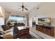 Bright living room with sliding doors to a balcony, tile floors, entertainment center, and cozy seating at 7179 Boca Grove Pl # 202, Lakewood Ranch, FL 34202