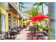 Charming outdoor cafe seating with vibrant red and yellow umbrellas providing shade, perfect for enjoying the neighborhood at 7179 Boca Grove Pl # 202, Lakewood Ranch, FL 34202