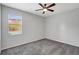 Neutral bedroom with a ceiling fan, carpet flooring, and view of the backyard through a window at 7705 55Th E St, Ellenton, FL 34222