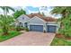 Charming gray home with a brick driveway, complemented by lush landscaping and mature palm trees at 7705 55Th E St, Ellenton, FL 34222