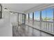 Bright sunroom featuring gray wood-look floors, white plantation shutters, and sliding glass doors to another room at 8710 54Th W Ave # 8710, Bradenton, FL 34210