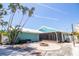 Charming exterior of the home with a unique turquoise paint scheme and metal roof, complemented by palm trees at 1021 Estremadura Dr, Bradenton, FL 34209