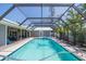 An enclosed in ground pool is surrounded by a brick patio and tropical plants at 1021 Estremadura Dr, Bradenton, FL 34209