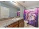 Well-lit bathroom featuring a granite vanity and shower with dolphin-themed shower curtain at 10944 Rainbow Pyrite Dr, Wimauma, FL 33598