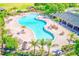 Aerial view of a resort-style pool area with a clubhouse, palm trees, and plenty of lounge chairs at 10944 Rainbow Pyrite Dr, Wimauma, FL 33598