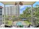 Inviting screened balcony with chairs and a view of lush greenery, the building and a sparkling community pool at 1100 Imperial Dr # 403, Sarasota, FL 34236
