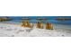 Relaxing beachfront featuring yellow Adirondack chairs on a sandy shore with calm turquoise waters at 1100 Imperial Dr # 403, Sarasota, FL 34236