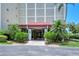 Building entryway with a red awning, beautiful landscaping, and intricate architectural details providing a stylish welcome at 1100 Imperial Dr # 403, Sarasota, FL 34236