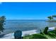 Two Adirondack chairs sit near blue water with palm trees in the distance at 1100 Imperial Dr # 403, Sarasota, FL 34236