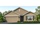 Beautiful, one-story home featuring a 2-car garage, tan and brown color scheme, and lush landscaping at 12075 Mountain Island Trl, Parrish, FL 34219