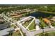 Aerial view of a neighborhood featuring a pond, lush green trees, well-maintained lawns, and beautiful single-Gathering homes at 12116 Stuart Dr, Venice, FL 34293