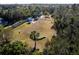 Aerial view of a fenced dog park with play structures and benches, surrounded by lush greenery at 12116 Stuart Dr, Venice, FL 34293