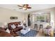 Cozy living room featuring a leather sectional, ceiling fan, and adjacent bar with views of the lanai at 12116 Stuart Dr, Venice, FL 34293
