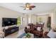 Living room featuring tan tile floors, a ceiling fan, and a large television at 12116 Stuart Dr, Venice, FL 34293