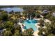 Aerial view of a pool surrounded by palm trees, featuring a water slide and nearby lake at 12116 Stuart Dr, Venice, FL 34293