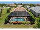 Aerial view of a pristine screened-in pool with brick patio and lush landscaping, offering a private outdoor oasis at 12116 Stuart Dr, Venice, FL 34293