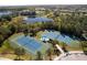 Aerial view of blue and green tennis courts with shelters, nestled in a community near a pond at 12116 Stuart Dr, Venice, FL 34293