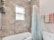 Bathroom featuring stylish tiled shower and tub with window, along with coordinating shower curtain and towels at 16411 62Nd E Gln, Parrish, FL 34219