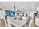 Open-concept living area features a modern kitchen island, blue accent wall, and dining area with elegant chandelier at 16411 62Nd E Gln, Parrish, FL 34219