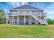 Backyard view of a house featuring dual balconies, white railings, stairs, and a spacious yard at 217 22Nd Street Ne Ct, Bradenton, FL 34208