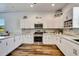 Modern kitchen showcasing stainless steel appliances, white cabinets, a stylish backsplash, and hardwood floors at 217 22Nd Street Ne Ct, Bradenton, FL 34208