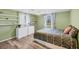 Inviting bedroom with green walls, wood floors, dresser, floating shelves, and natural light from the windows at 217 High Point Dr # 217A, Englewood, FL 34223