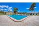 Community pool area featuring a pool with an access ladder, surrounded by green landscaping and clear blue sky at 217 High Point Dr # 217A, Englewood, FL 34223