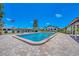 Community pool with clear blue water, surrounded by a brick patio and palm trees under a clear sky at 217 High Point Dr # 217A, Englewood, FL 34223