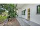 Side angle of the exterior showing the walkway to the door and the gravel yard with tropical landscaping at 2516 Goldenrod St, Sarasota, FL 34239