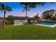 Lush green backyard featuring a refreshing swimming pool, screened-in porch, and well-maintained lawn at 2915 Woodpine Cir, Sarasota, FL 34231