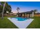 Backyard pool with white tile surround and adjacent screened-in porch and lush lawn at dusk at 2915 Woodpine Cir, Sarasota, FL 34231