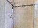 Modern shower with neutral tile and decorative accent stripe, along with shower niche, and glass surround at 4115 2Nd Nw Ave, Bradenton, FL 34209