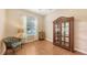 This bedroom features hardwood floors, a curio cabinet, and a window for natural light at 4274 Tennyson Way, Venice, FL 34293