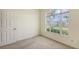 Empty room with a large window showcasing lush greenery and a door at 4274 Tennyson Way, Venice, FL 34293