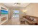 Living room with tile flooring, leather sofa, and sliding glass doors to the pool area at 4274 Tennyson Way, Venice, FL 34293