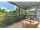 Covered and screened balcony with outdoor chairs and view of the trees at 4500 Chinkapin Dr, Sarasota, FL 34232