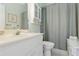 Bright bathroom with a gray shower curtain and white cabinets at 4804 Jacaranda Heights Dr, Venice, FL 34293