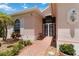 Inviting front entrance with an arched window, brick pathway, security door and lush landscaping at 4804 Jacaranda Heights Dr, Venice, FL 34293