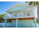 Charming coastal home featuring a large elevated porch, light blue siding, and a ground-level garage at 507 Spring Ave, Anna Maria, FL 34216